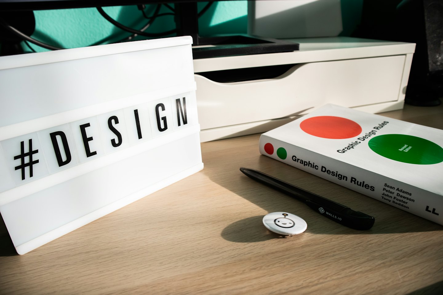 Design workspace with light box, book, and pen on a desk.